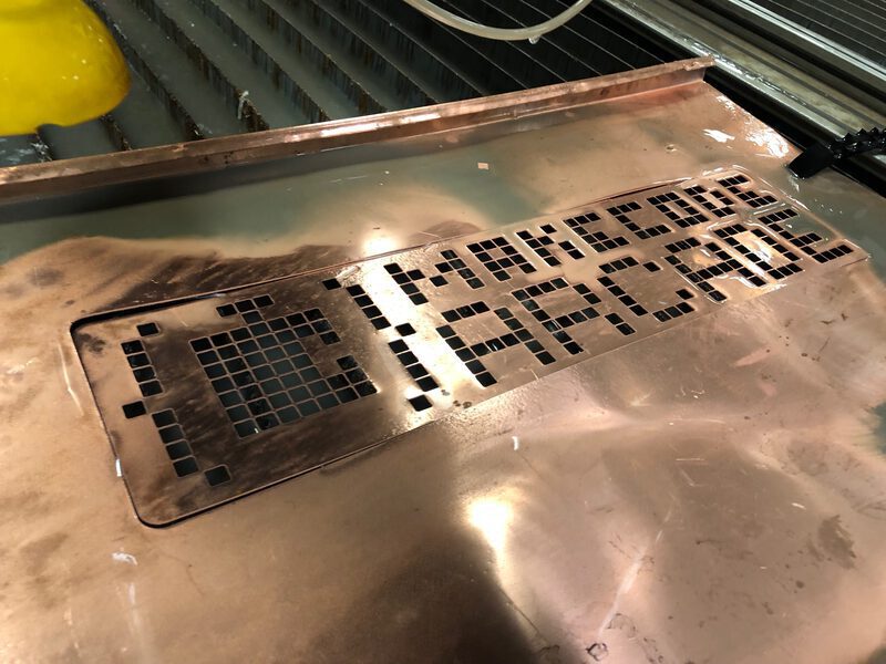 A MakeCode Arcade logo cut out of a copper sheet
